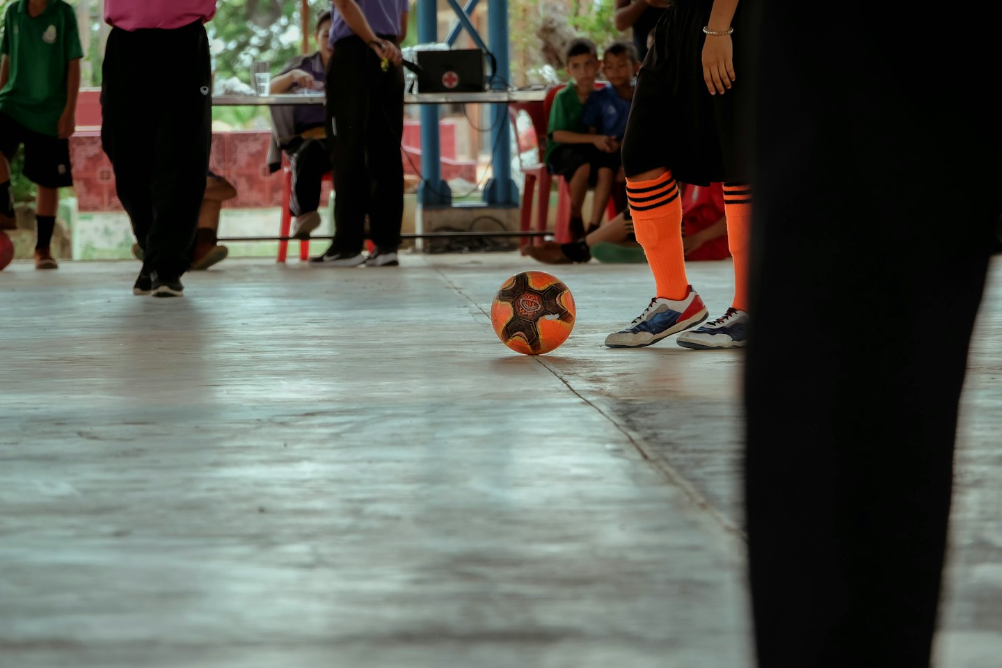 Jugador de fútbol sala con calcetines naranjas de pie sobre un balón.